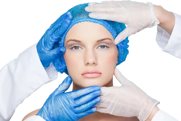 Surgeons examining content blonde wearing blue surgical cap — Stock Photo, Image