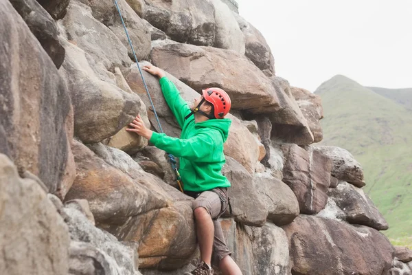 Hombre en forma escalando una gran cara de roca —  Fotos de Stock