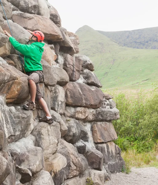 Focused man ascending a large rock face — Stock Photo, Image