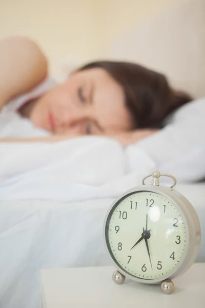 Meisje slaapt in haar bed met een wekker op voorgrond — Stockfoto