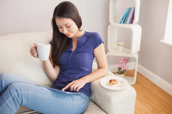 Joven sonriente mujer asiática usando su tableta pc y sosteniendo taza de café — Foto de Stock