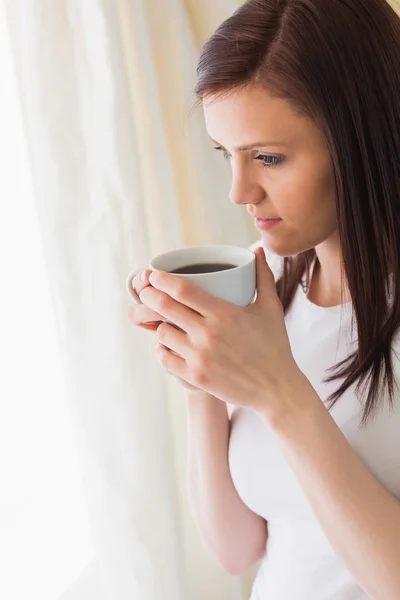 Omtänksamt flicka håller en kopp kaffe och tittar bort — Stockfoto