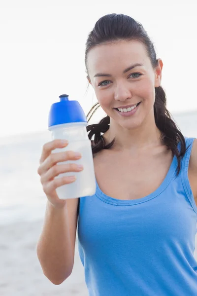 Lachende vrouw toont haar fles water — Stockfoto