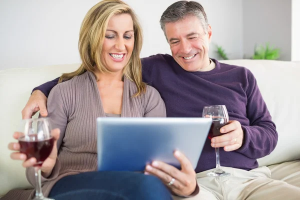 Glückliches Paar schaut seinem Tablet-PC zu und trinkt Wein — Stockfoto