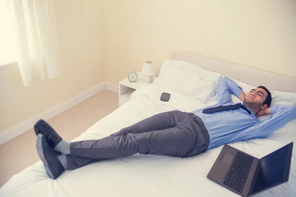 Удовлетворенный мужчина отдыхает на кровати — стоковое фото