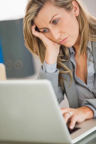 Jaded affärskvinna tittar på sin laptop på ett kontor — Stockfoto