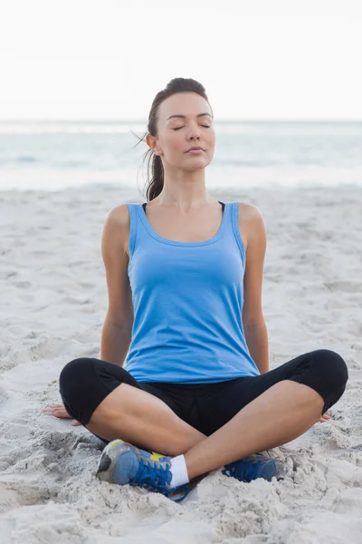 Sportliche Frau sitzt im Sand — Stockfoto