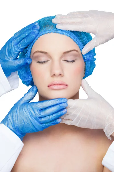 Χειρουργοί εξέταση ειρηνική νεαρή ξανθιά φορώντας μπλε καπάκι — Φωτογραφία Αρχείου