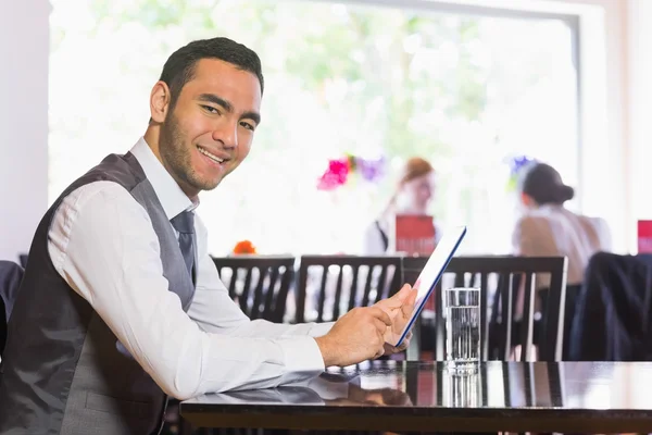 Empresário feliz usando tablet e sorrindo para a câmera — Fotografia de Stock