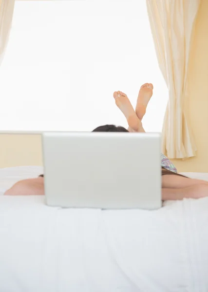 女孩躺在一张床后面一台笔记本电脑 — 图库照片