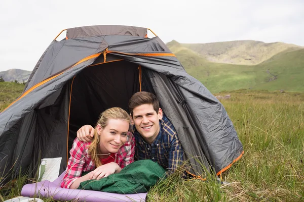 テントの中で横になっていると、カメラを見て幸せなカップル — ストック写真