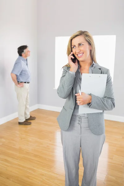 Smiling realtor calling someone with her mobile phone — Stock Photo, Image