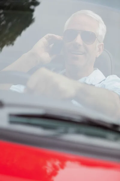 Cheerful handsome man in red convertible having phone call — Stock Photo, Image