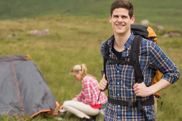 Neşeli adam kız arkadaşı çadır yunuslama iken sırt çantası taşıyan — Stok fotoğraf