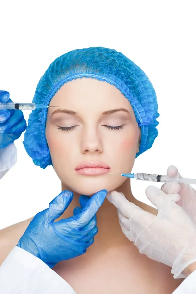 Хирурги делают укол мирной блондинке в синей хирургической шапке — стоковое фото