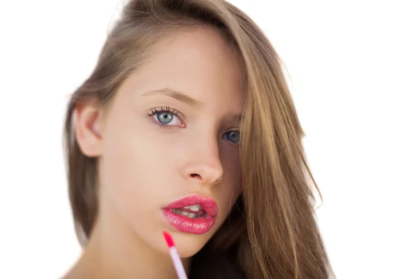 Serious brunette model applying pink gloss on her lips — Stock Photo, Image