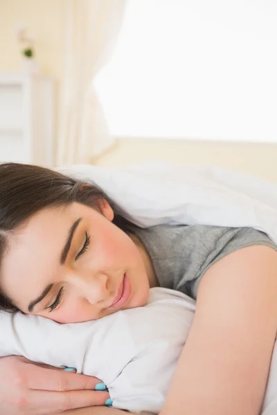 Sonriente chica durmiendo en su cama — Foto de Stock