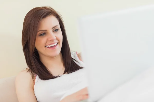 Laughing girl looking and using a laptop lying on a bed — Stock Photo, Image