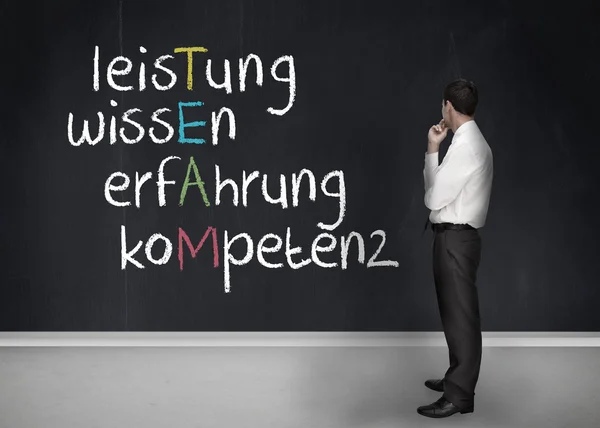 Элегантный бизнесмен смотрит на доску с командной анаграммой на немецком языке — стоковое фото