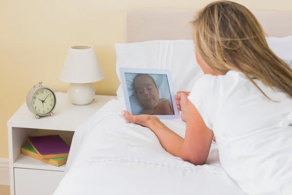 Fokuserad kvinna med en TabletPC liggande på hennes säng — Stockfoto