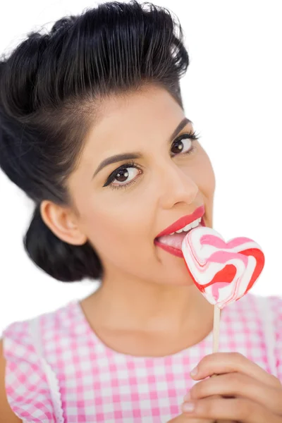 Cheerful black hair model licking a heart shaped lollipop — Stock Photo, Image