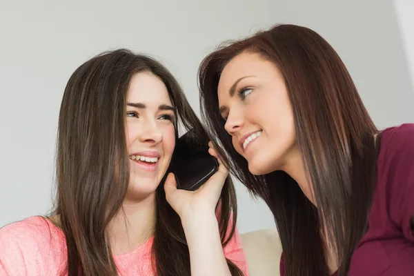 Två glada tjejer ringer någon med en mobiltelefon — Stockfoto