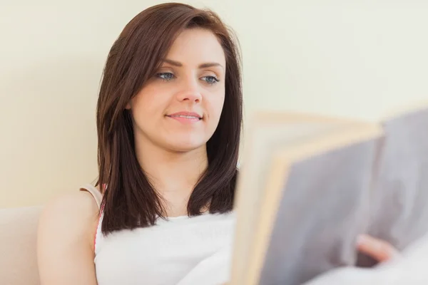 Glückliches Mädchen liest ein Buch, das auf einem Bett liegt — Stockfoto