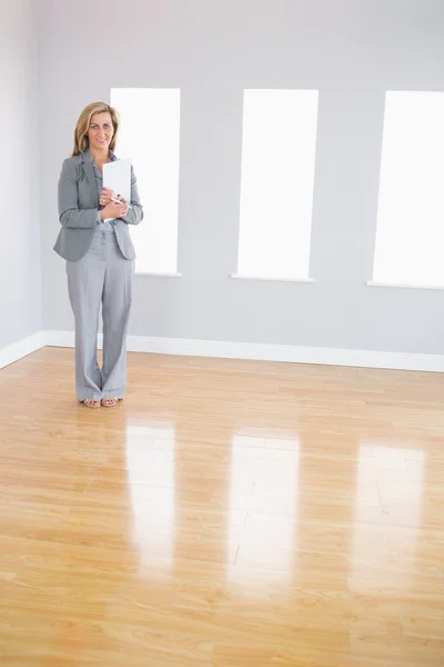 Happy realtor standing in a room holding documents — Stock Photo, Image