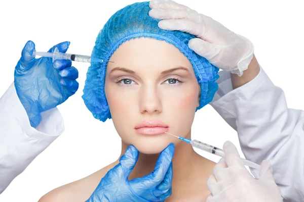 Cirurgiões fazendo injeção em muito loira vestindo tampa cirúrgica azul — Fotografia de Stock