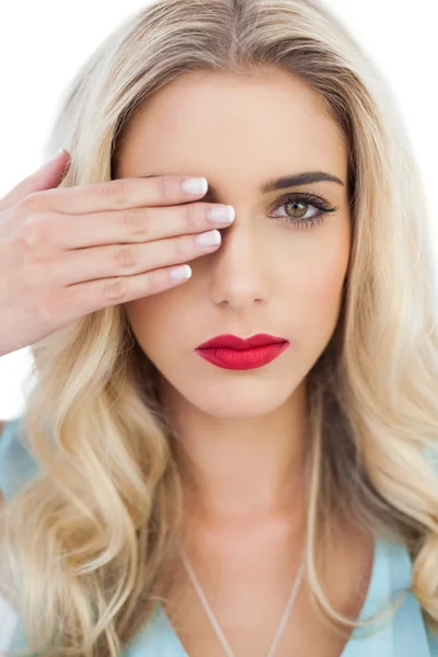 Blondes Model in blauem Kleid blickt mit einem Auge in die Kamera und versteckt das andere mit der Hand — Stockfoto