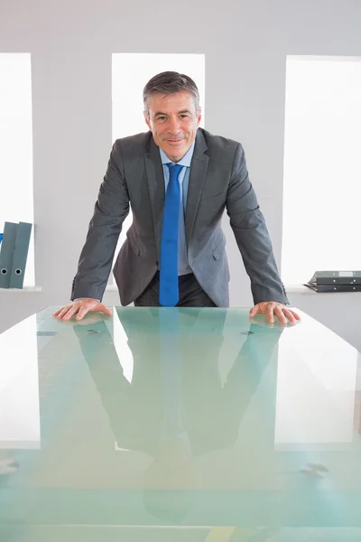 Смеющийся бизнесмен, стоящий перед столом — стоковое фото