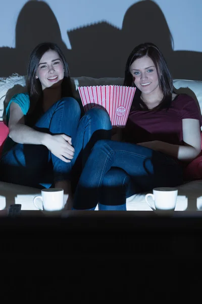 Dva usmívající se přátelé na gauči, sledování televize společně ve tmě — Stock fotografie
