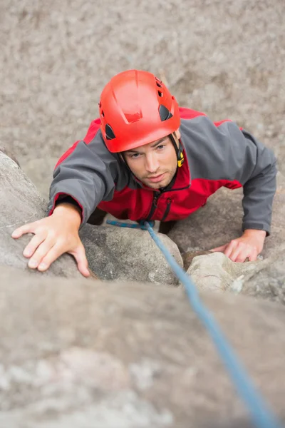 Uomo concentrato arrampicata parete di roccia — Foto Stock