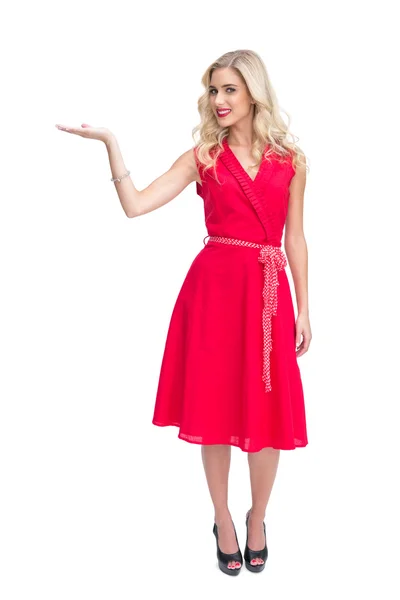 Glad kvinna i röd klänning presentera något i handen — Stockfoto