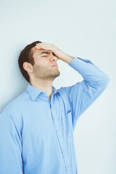 Aufgebrachte Männeraugen geschlossen und eine Hand auf der Stirn an eine Wand gelehnt — Stockfoto