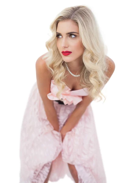 Pensant modèle blonde en robe rose posant les mains sur les cuisses — Photo