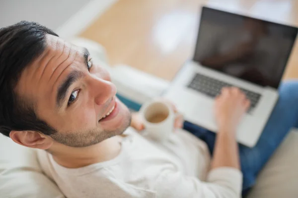 Vista ad alto angolo del giovane sorridente che usa il suo computer portatile — Foto Stock