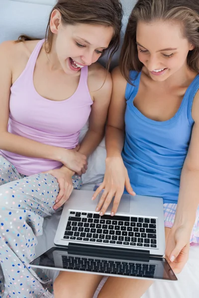 Girls sitting on bed using laptop — Stock Photo, Image