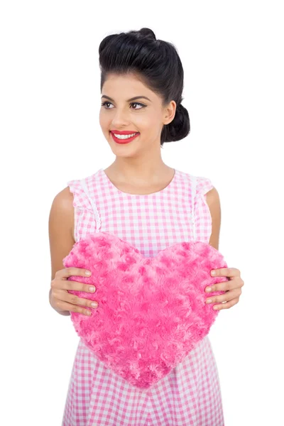 Joyeux modèle de cheveux noirs tenant un oreiller rose en forme de coeur — Photo