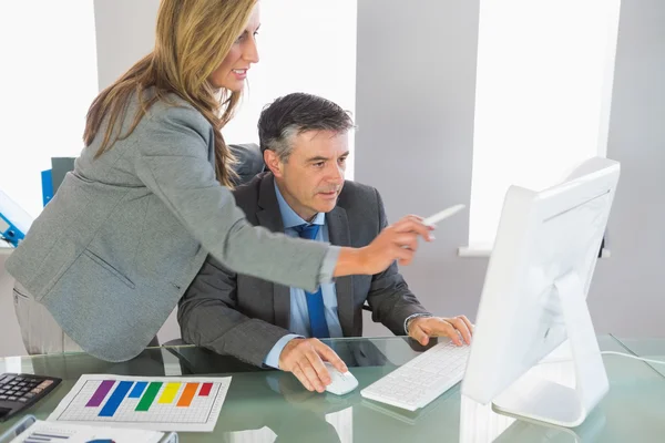 Businesswoman explaining something on the computer to a concentrated businessman — Stock Photo, Image