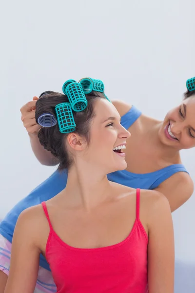 Girls wearing hair rollers sitting in bed — Stock Photo, Image