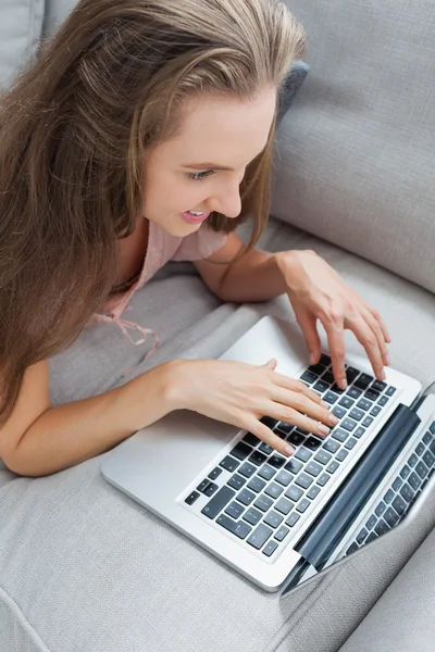 Vista aerea della donna casuale che utilizza il computer portatile sul divano — Foto Stock