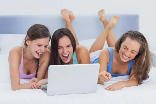 Friends lying on bed with laptop — Stock Photo, Image