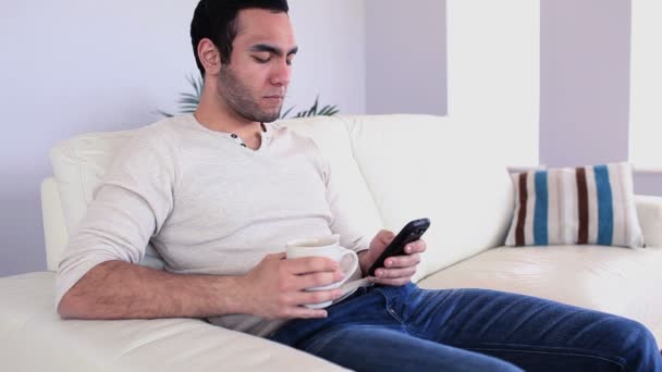 Bonito homem enviando uma mensagem bebendo café — Vídeo de Stock