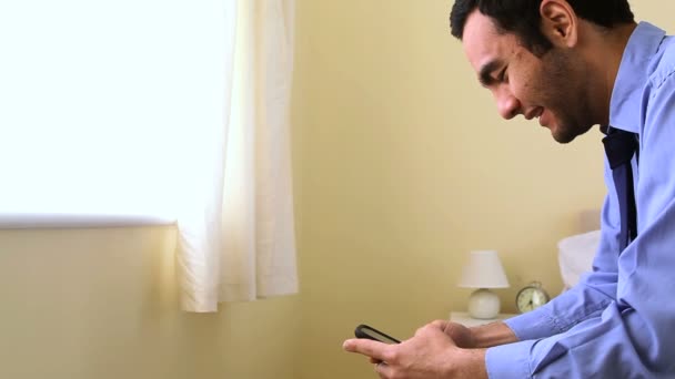 Портрет бизнесмена, переписывающегося со своим смартфоном в постели — стоковое видео