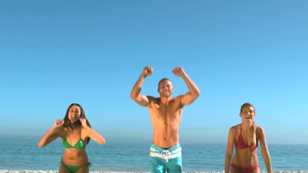 Attraktive Freunde, die gleichzeitig am Strand springen — Stockvideo