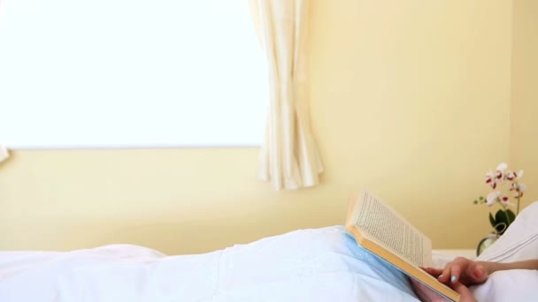 Retrato de una mujer leyendo un libro azul en la cama — Vídeos de Stock