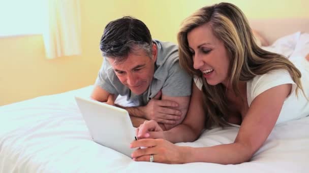 Couple d'âge mûr couché sur le lit regardant tablette numérique — Video