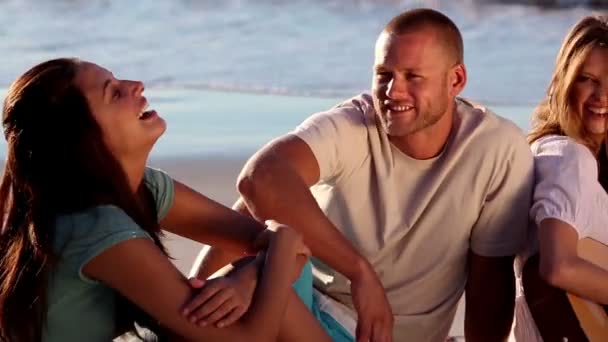 Amigos sonrientes sentados en la playa — Vídeo de stock