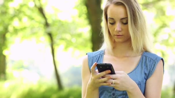 Hermosa adolescente enviando un texto en su teléfono inteligente — Vídeos de Stock